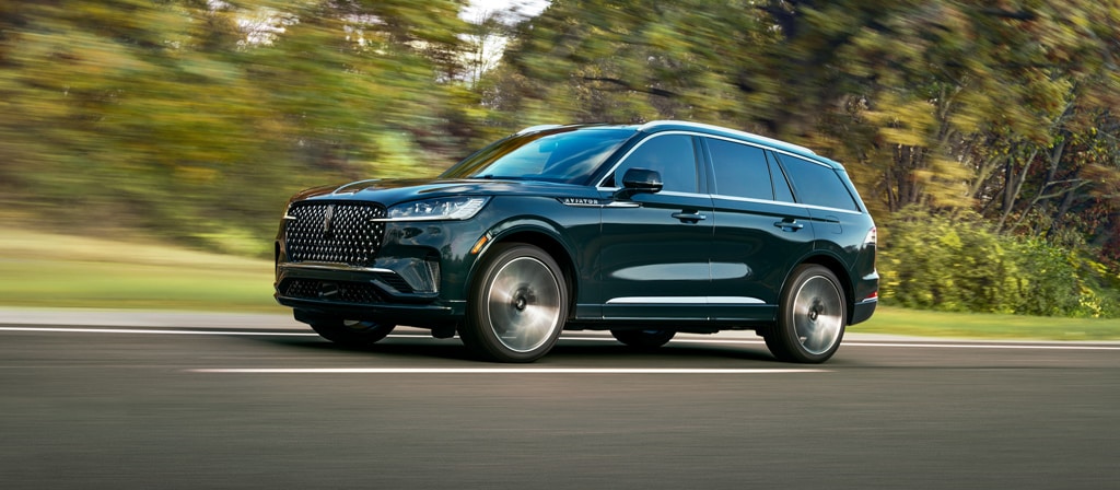 Un Lincoln Aviator® Black Label® 2027 roulant dans une campagne luxuriante