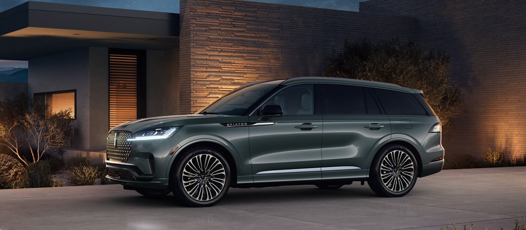 Un Lincoln Aviator® Black Label® 2027 stationné à côté d’une maison moderne la nuit