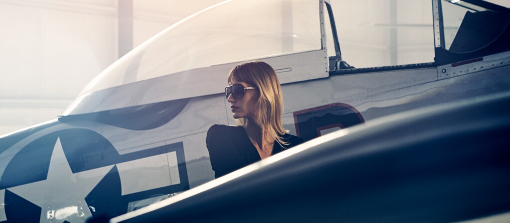 Une femme devant un avion d’époque dans un hangar privé