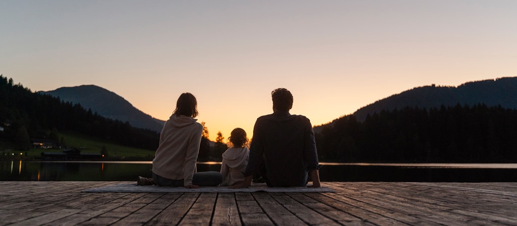 Une famille assise à l’extérieur au coucher du soleil, dans l’attente du lever de la lune