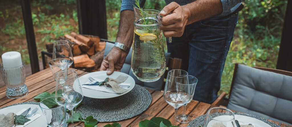 Un homme dresse une table à l’extérieur en prévision de l’arrivée de ses invités