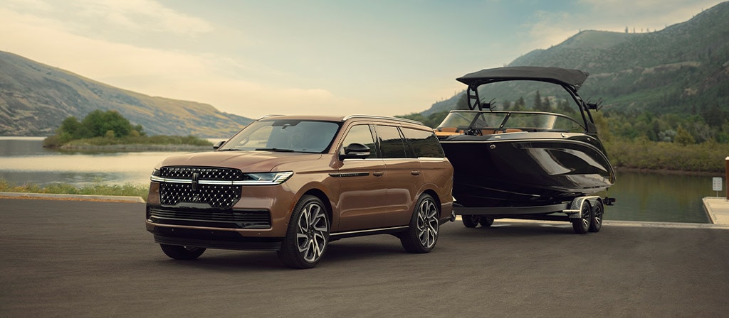 Un Lincoln Navigator® Black Label 2026 remorque un bateau au bord de l'eau