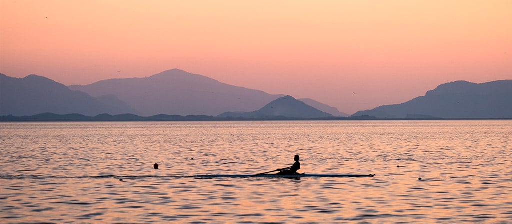 Une personne rame dans un skiff sur l'océan le matin
