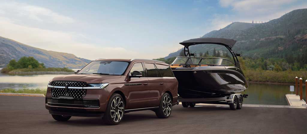Un modèle Lincoln Navigator® Black Label™ 2027 a un bateau attelé au bord de l’eau
