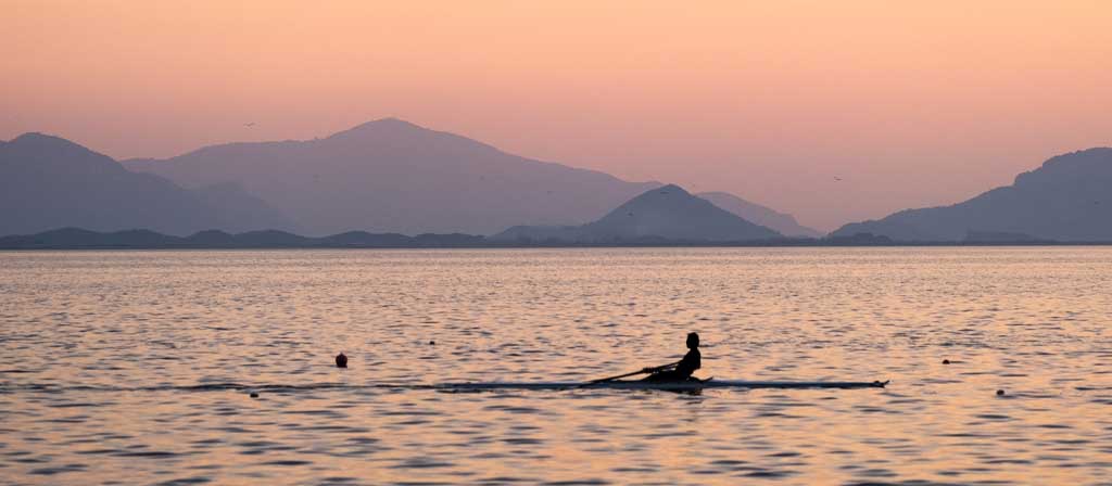 Une personne rame un bateau d’aviron sur l’océan le matin