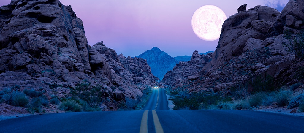 La lune se lève au-dessus d’une autoroute du Sud-Ouest désertique la nuit.