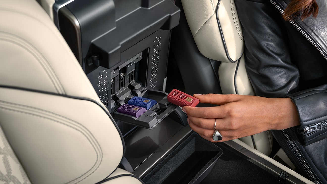 Gros plan sur une main insérant une cartouche de Parfum Numérique Lincoln dans une fente située à l’intérieur de la console centrale.