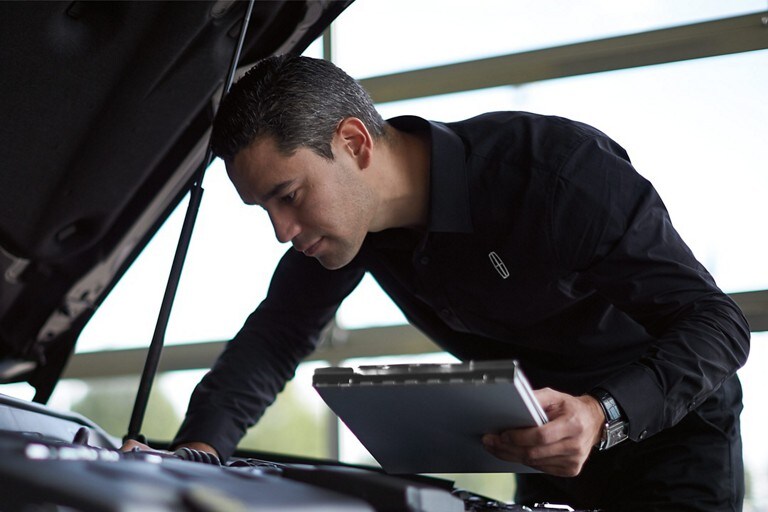Un technicien d'entretien Lincoln inspecte le moteur d'un véhicule Lincoln dans le cadre d'une inspection en 200 points