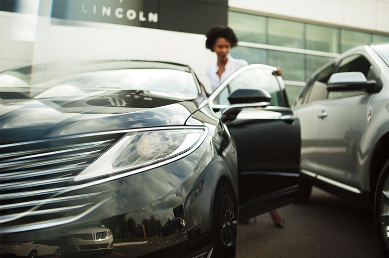 Un client ouvre la portière d'un véhicule Lincoln chez un concessionnaire