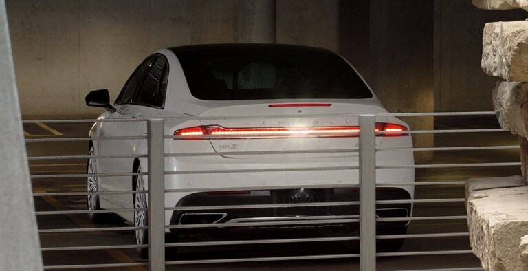 Un Lincoln MKZ blanc reculant dans un garage de stationnement démontrant la fonction Systèmes de détection à l’avant et à l’arrière