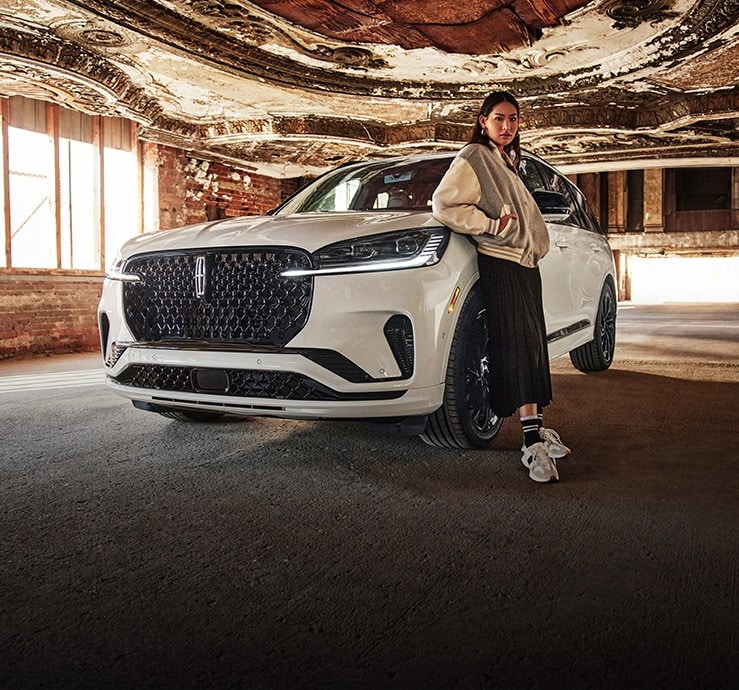 Une femme debout devant un véhicule Lincoln.