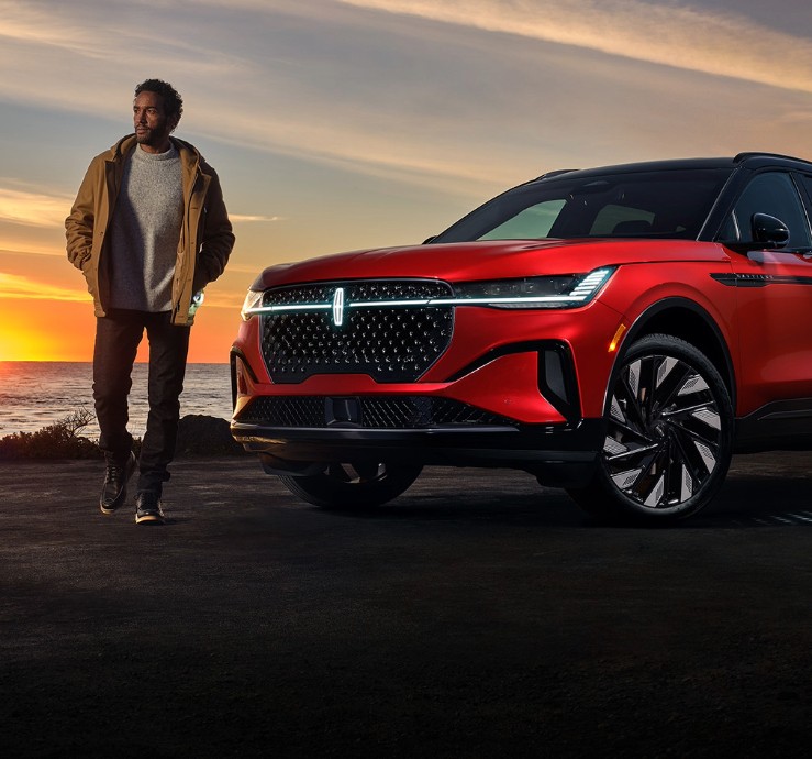 Un homme debout à l'extérieur d'un Lincoln Nautilus stationné près d'un cours d'eau.