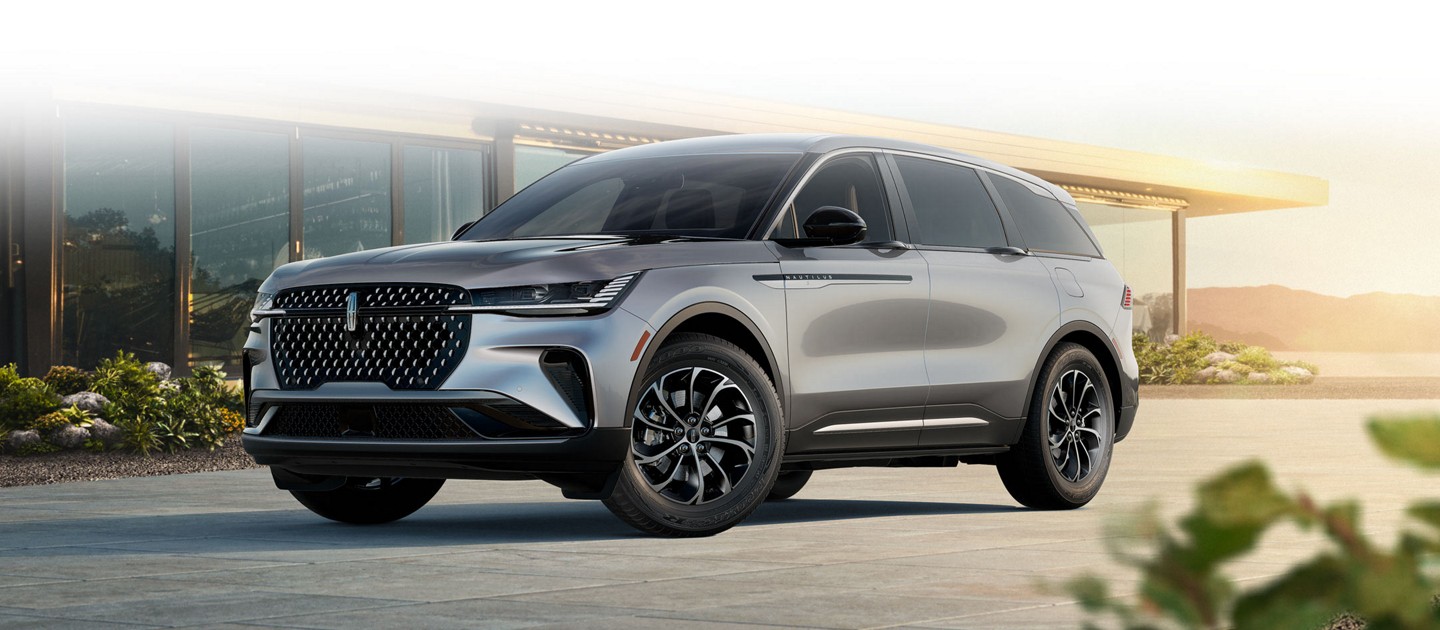 Un Lincoln Nautilus Première 2025 en gris lustré est stationné dans une entrée au coucher du soleil