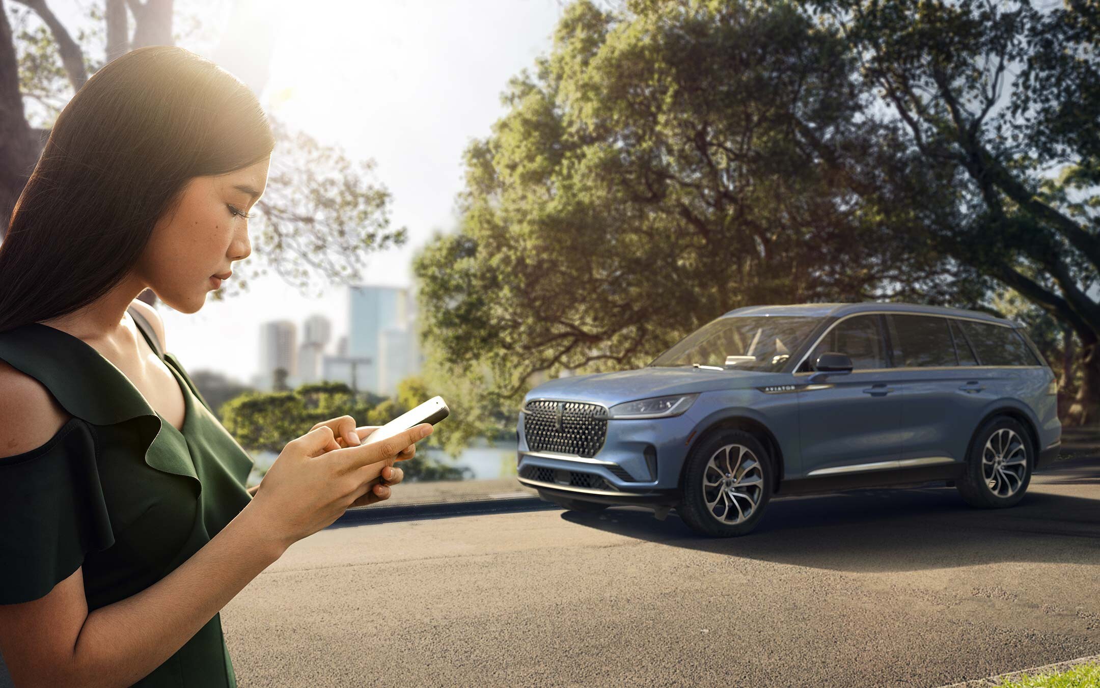 Une femme utilise son téléphone en accédant à un point d'accès depuis son Lincoln Aviator