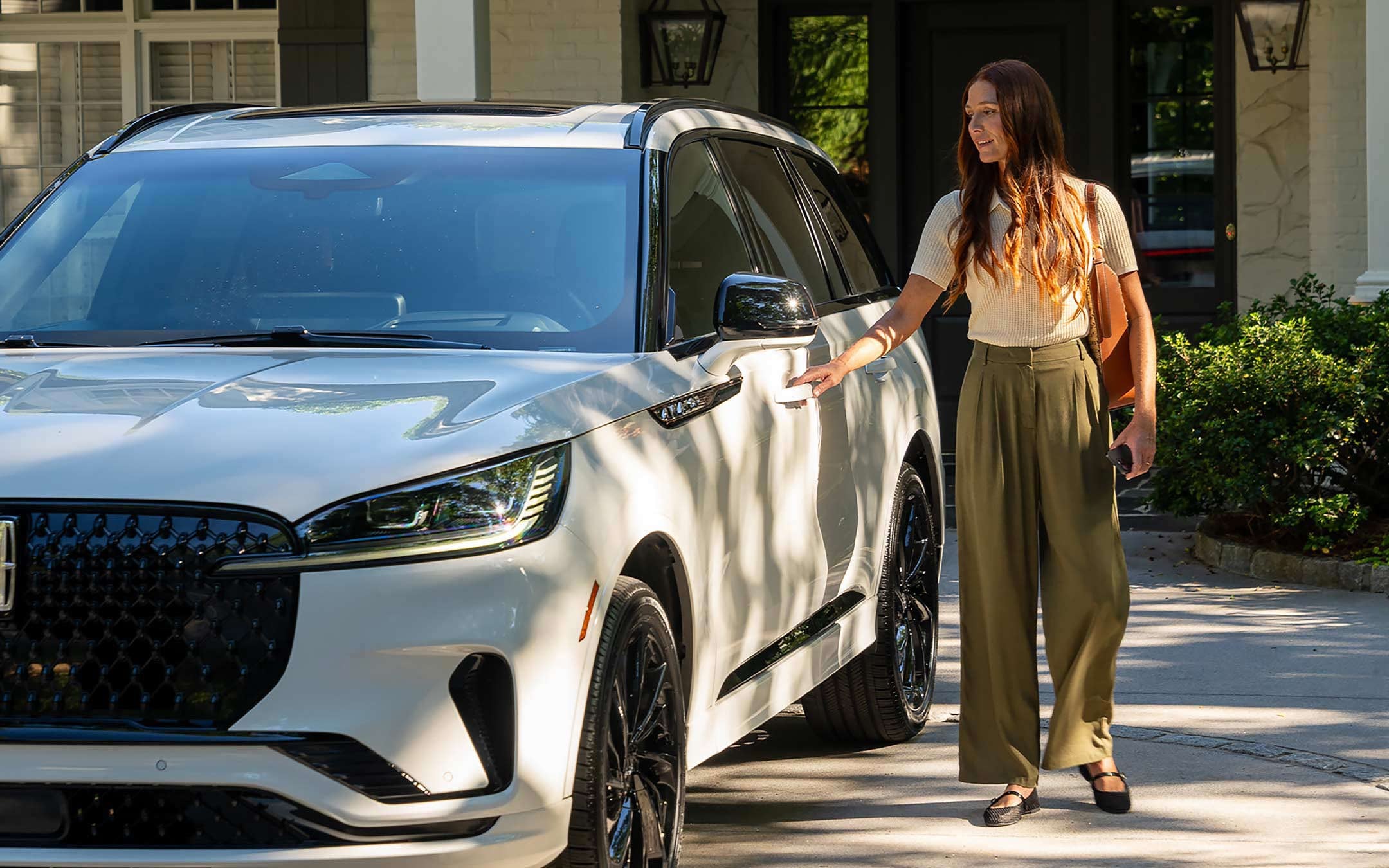 Une femme utilisant son téléphone intelligent comme clé pour verrouiller son Lincoln Aviator