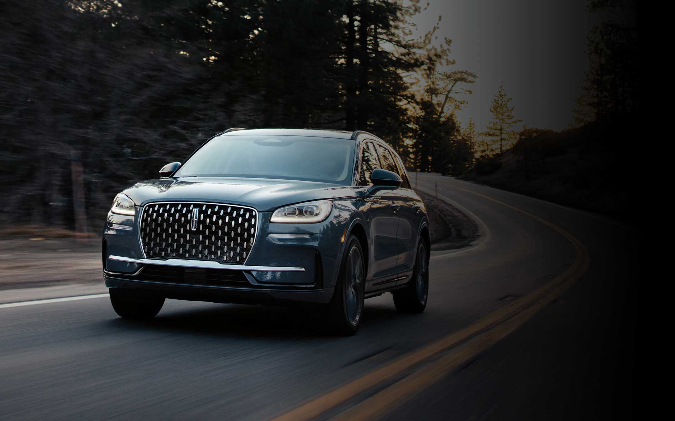 Le modèle Lincoln Corsair Ultra 2026 couleur extérieure bleu murmure est conduit sur une route de campagne