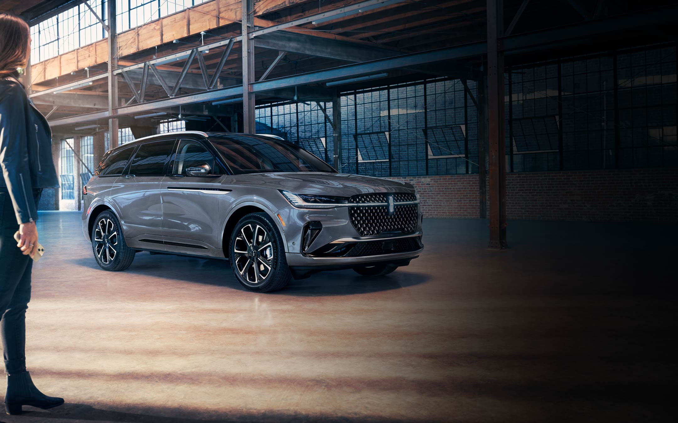 Une femme s’éloigne d’un VUS Lincoln Nautilus 2025, tandis que la séquence d’éclairage Lincoln Embrace éclaire le chemin