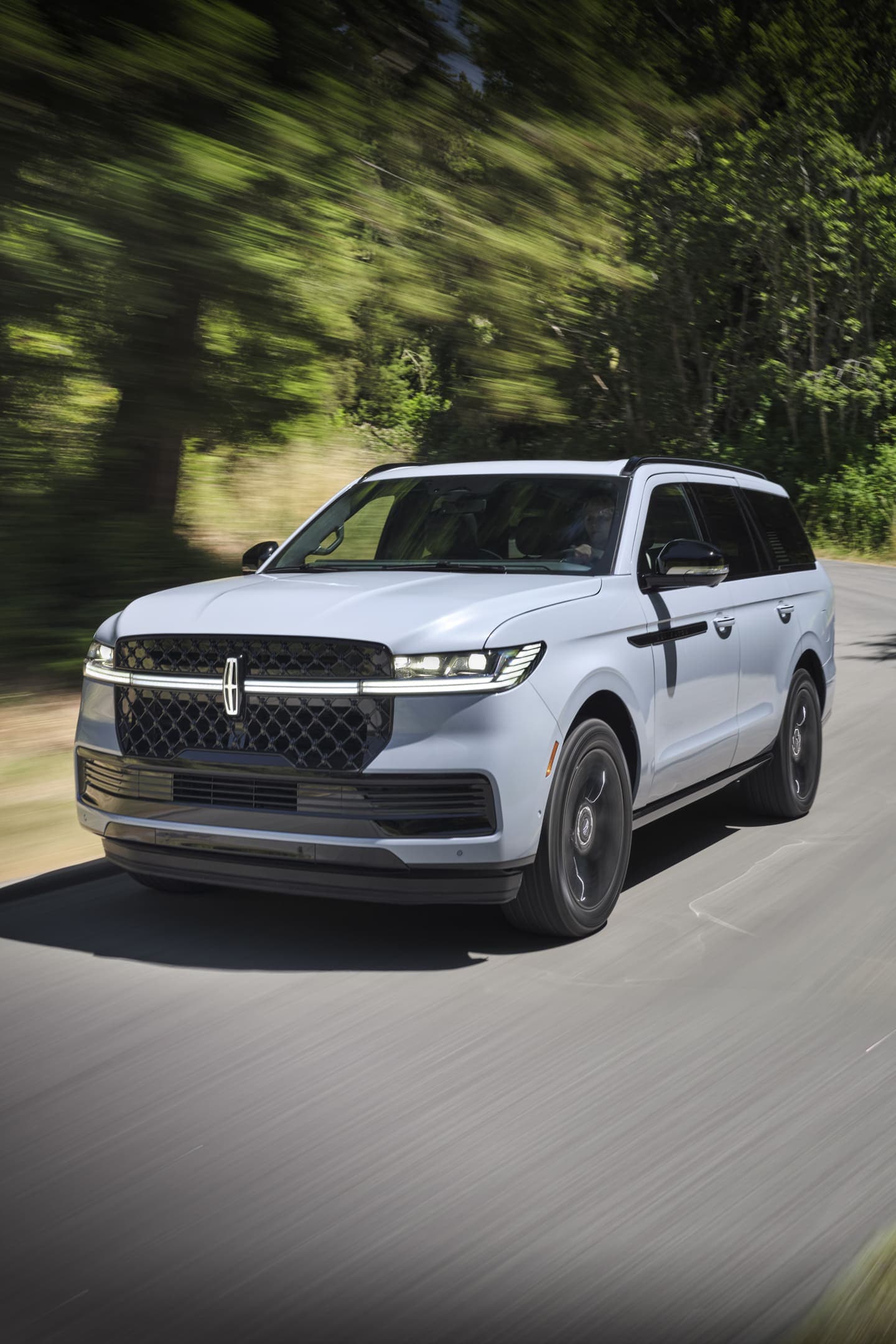 Un VUS Lincoln Navigator® 2025 circulant sur une route bordée d’arbres
