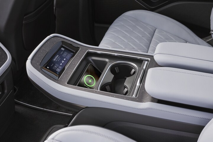 Un téléphone qui se recharge sur un tapis de recharge sans fil placé dans la console de la deuxième rangée d’un Lincoln Black Label Navigator® 2025.