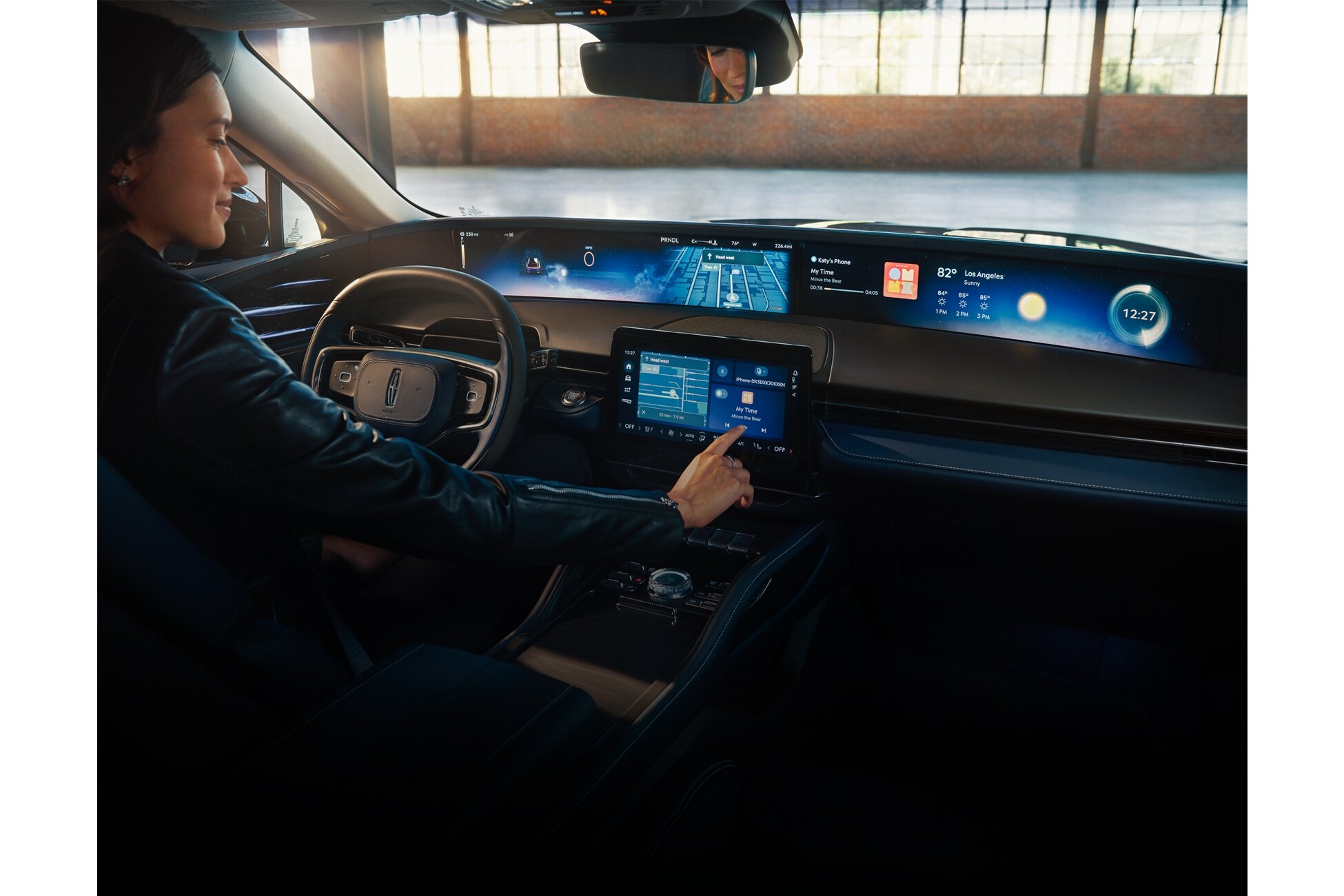 A person operates a Lincoln vehicle while tapping the center-stack display touchscreen.