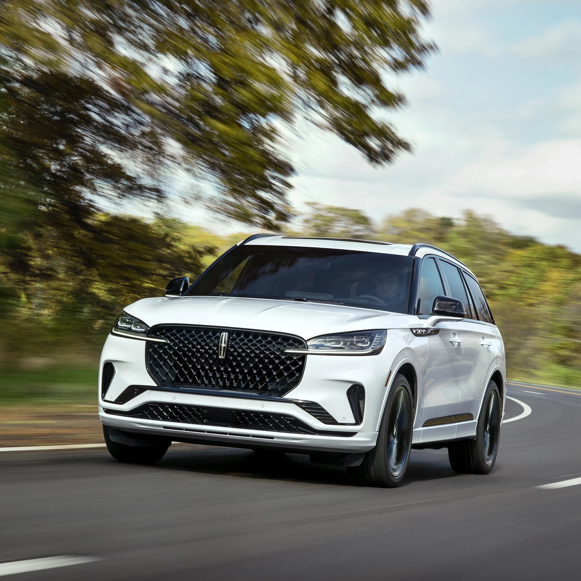 Un VUS Lincoln Aviator® 2026 circulant sur une route bordée d’arbres