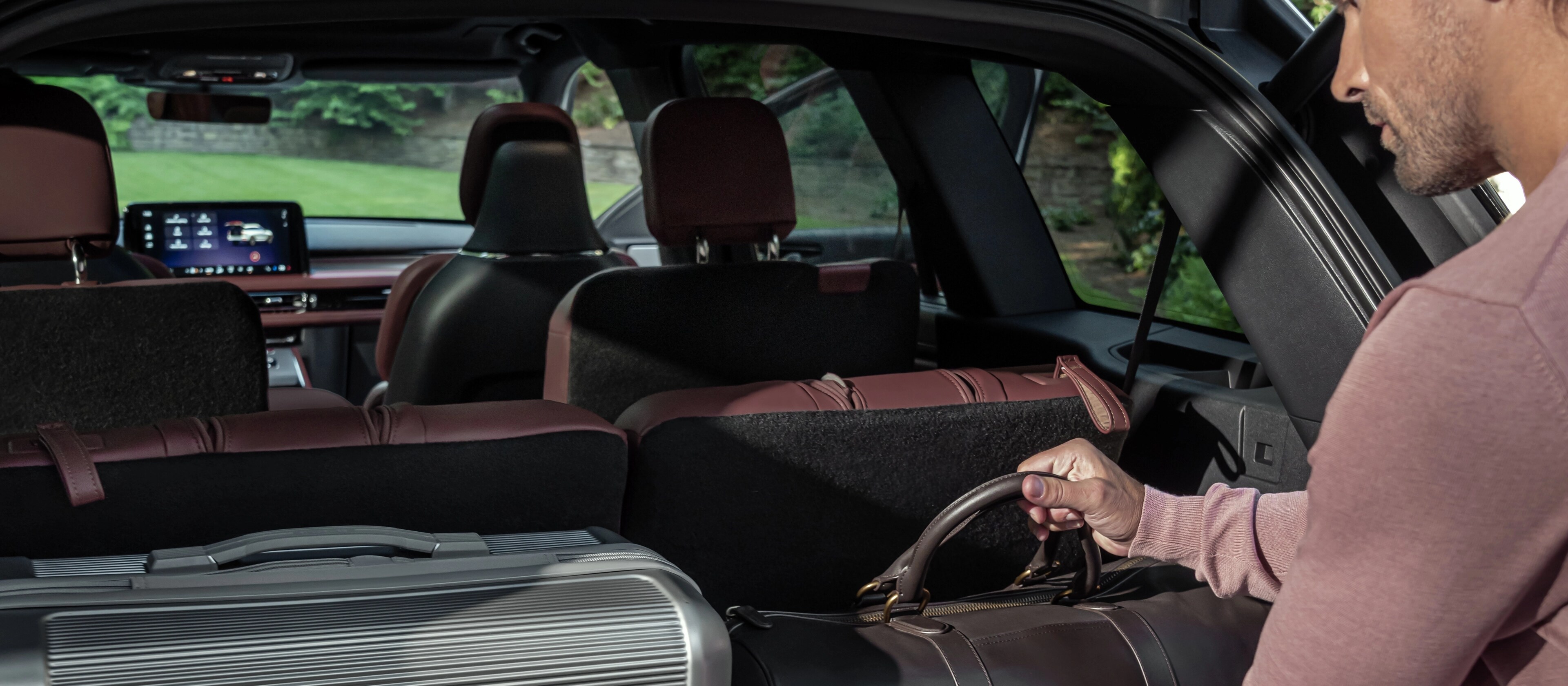 Une personne charge un sac en cuir dans la zone de chargement arrière d’un Lincoln Aviator 2026