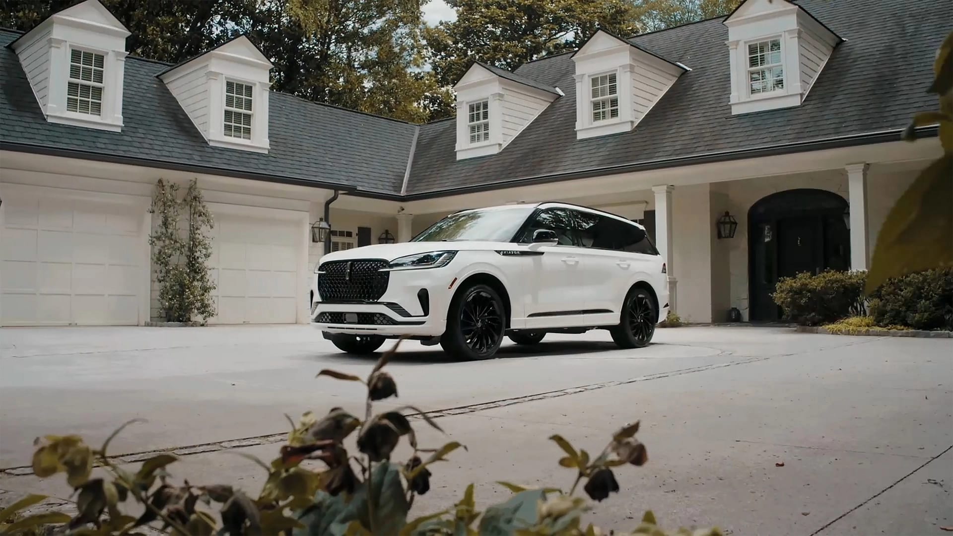Un Lincoln Aviator 2026 est stationné dans l’entrée d’une maison luxueuse