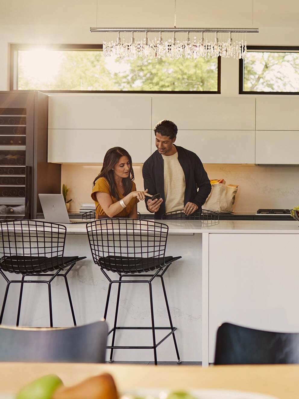 Un homme et une femme debout dans la cuisine et regardant un téléphone.