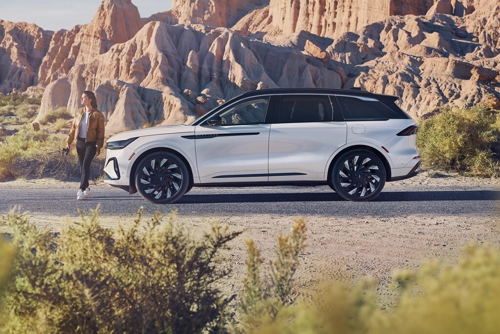 Un véhicule Lincoln stationné sur une route avec une femme marchant à côté.