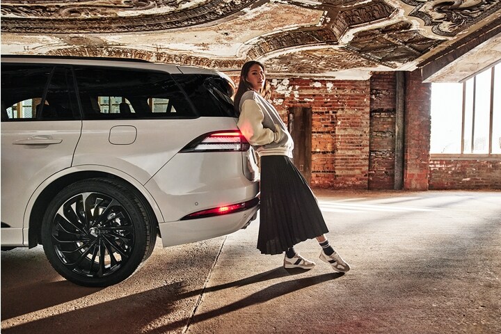 Une femme appuyée contre l'arrière du Lincoln Aviator 2025