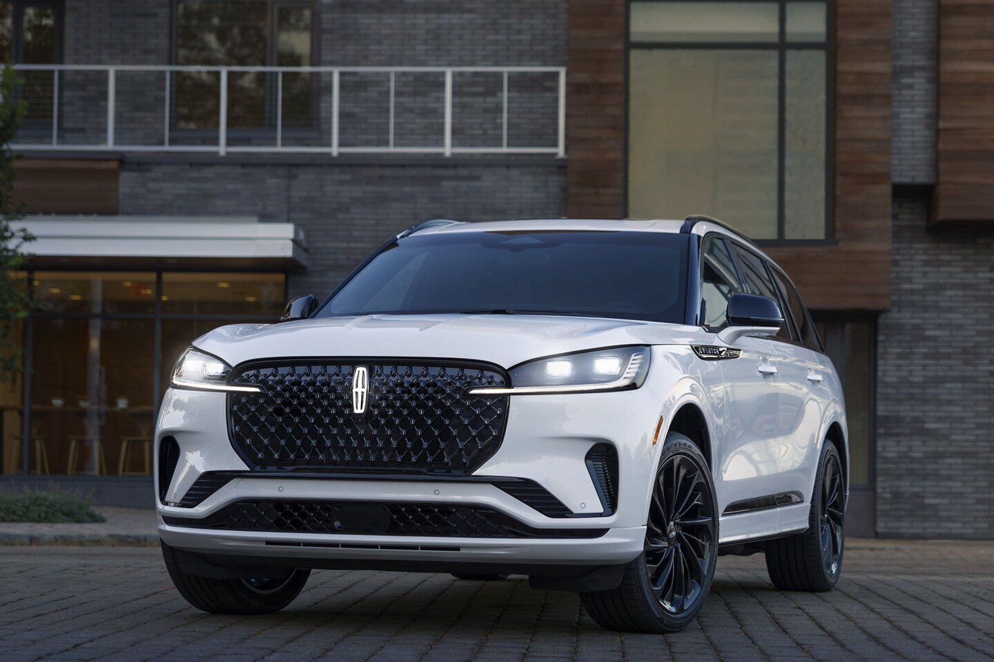 Un Lincoln Aviator Ultra 2025 est stationné devant un restaurant avec ses phares allumés