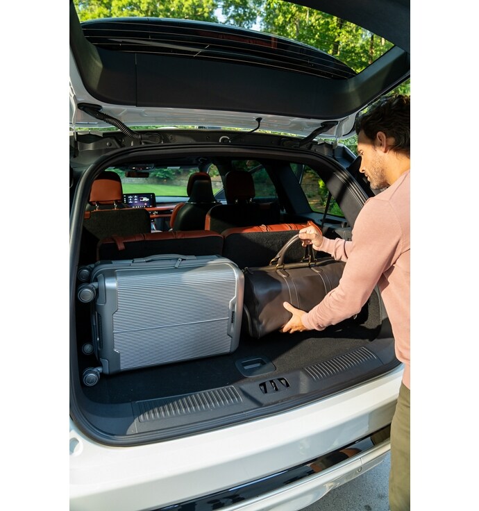 Un homme charge des bagages à l'arrière d'un VUS Lincoln Aviator® 2025 par le hayon arrière ouvert.