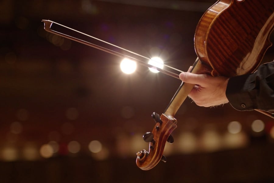 Une personne tire un coup d’archet sur la corde d’un violon, faisant allusion aux carillons d’un Lincoln Corsair 2025.