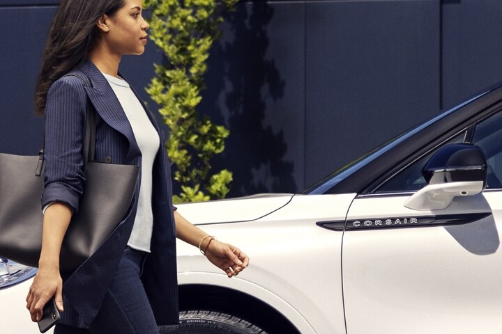 Une personne s’approche d’un Lincoln Corsair 2025 tenant un téléphone mobile.