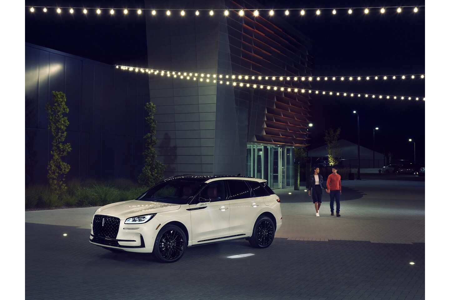 Un couple s’approche d’un Lincoln Corsair 2025 alors que l’éclairage Lincoln Embrace guide le chemin