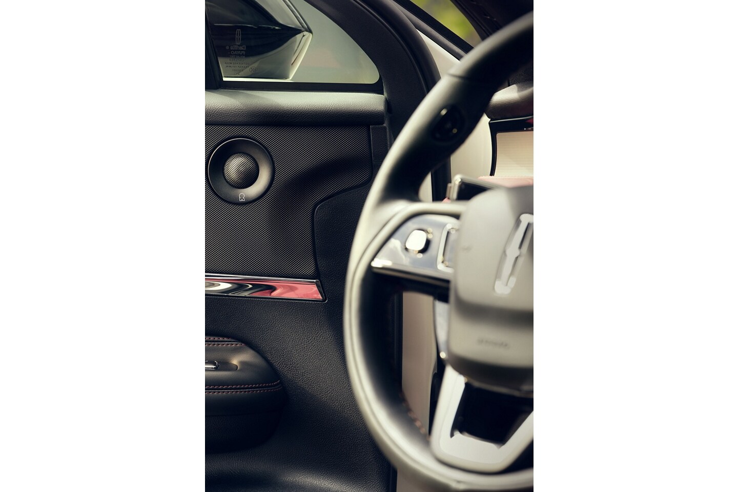 Un haut-parleur de milieu de gamme du système audio Revel à 14 haut-parleurs offert en option est illustré sur le panneau de porte avant du conducteur