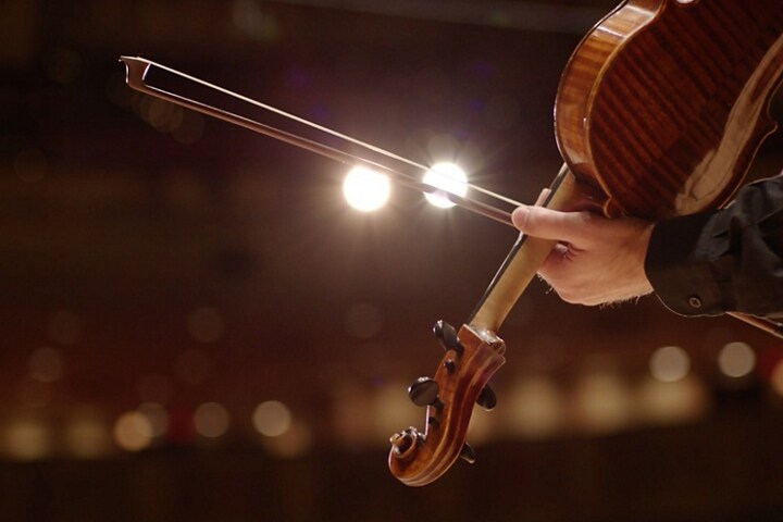 Une personne tire un coup d’archet sur la corde d’un violon, faisant allusion aux carillons d’un Lincoln Corsair 2026.
