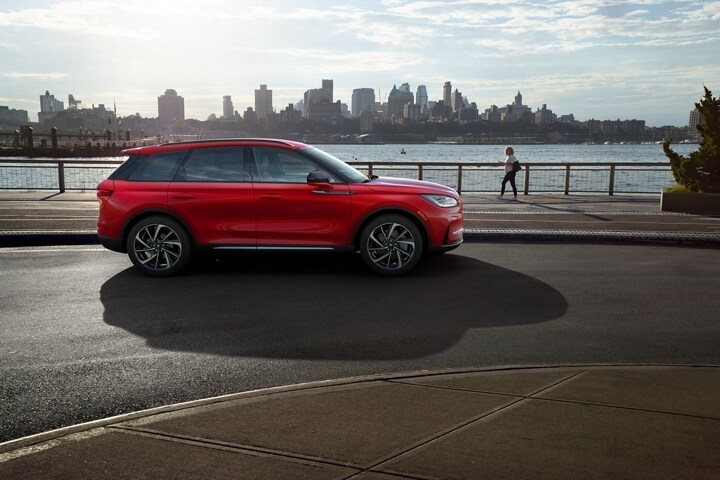 Un Lincoln Corsair 2026 de couleur extérieure tapis rouge est stationné à côté d’un parc au bord de l’eau