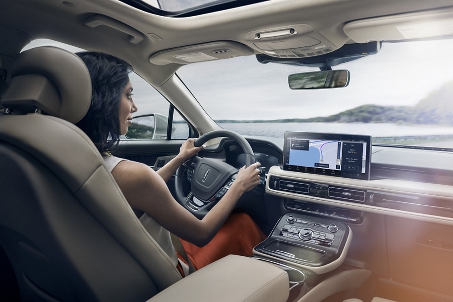 Une femme conduit un Lincoln Nautilus 2023 tandis que l’application de navigation sur l’écran tactile central guide son parcours