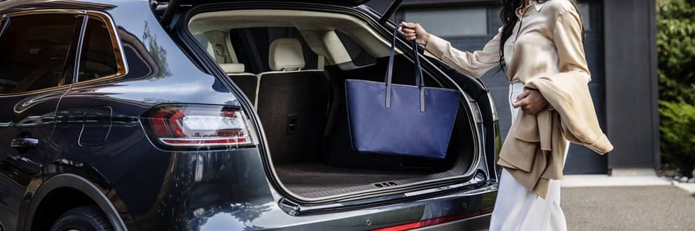 Une femme place un sac à main dans le coffre d'un véhicule Lincoln