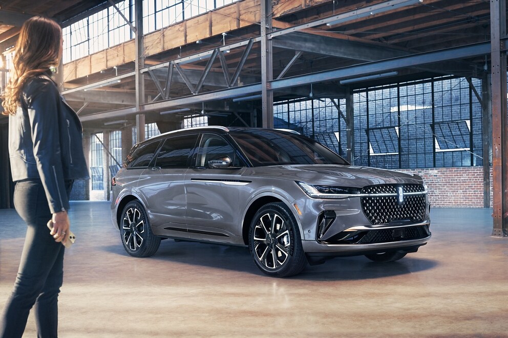 Un téléphone intelligent est tenu dans la main d’une femme alors qu’elle marche vers un VUS Lincoln Nautilus 2025