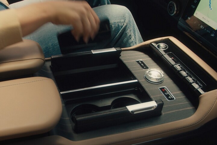 Le conducteur d’un Lincoln Black Label Navigator® 2025 s’étend pour placer un téléphone intelligent sur le tapis de recharge sans fil